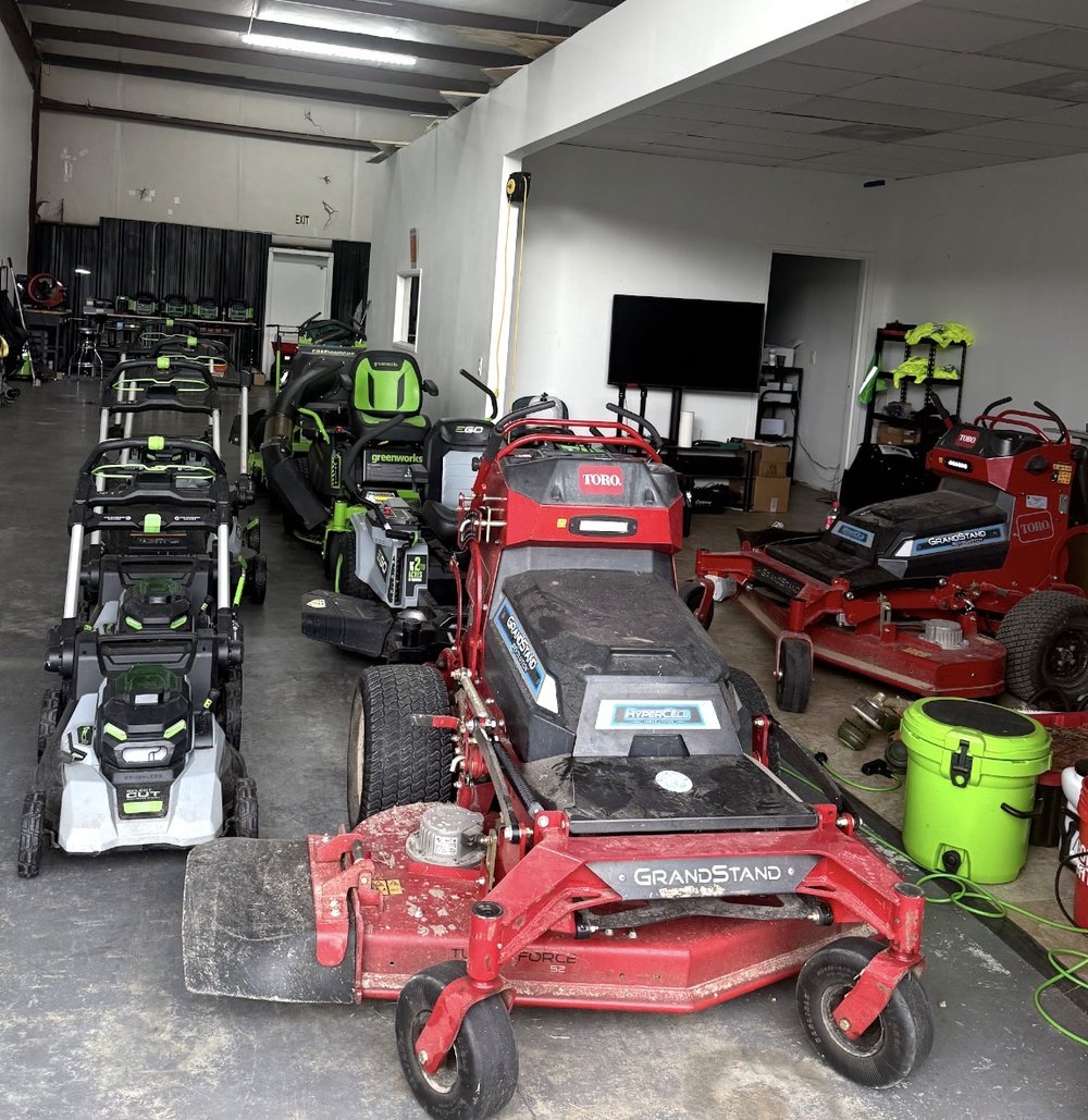 Toro GrandStand electric stand-on mowers, Greenworks and EGO electric mowers lined up in the QuietScapes shop