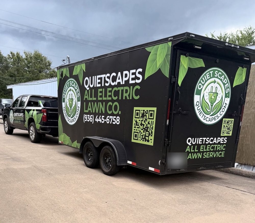 QuietScapes truck towing the black enclosed trailer wrapped with the QuietScapes All Electric Lawn Co. logo